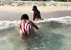 Two ebony women explore intimate beach pleasures in striped swimsuits