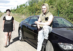 Perverted short haired mature brunette stands on knees to give BJ outdoors