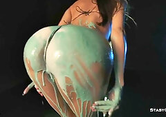 Slender brunette artistically poses nude with green body paint and black heels