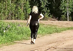 Undressed large booty in leather leggings on a walk in the park