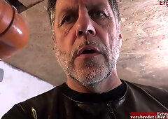 German dominatrix oversees a bondage session with a pierced submissive in an industrial dungeon