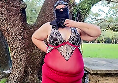 Curvy woman in red lingerie bends over picnic table in park