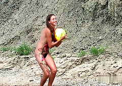 Slender nude women gather on a rocky shore for artistic bodypaint under open skies
