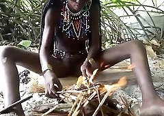Pretty tribe beauty making traditional jewelery next to a firecamp