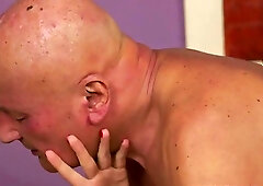 Sexy bitch is sucking a bald man’s massive cock, while he is fingering her pierced pussy
