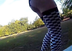 Crossdresser in short costume and heels walking around a park