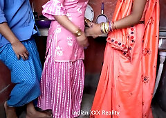 Indian couple shares intimate kitchen moment with a guest in traditional attire