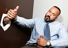 Doominant man plays with a businessman at the glory hole